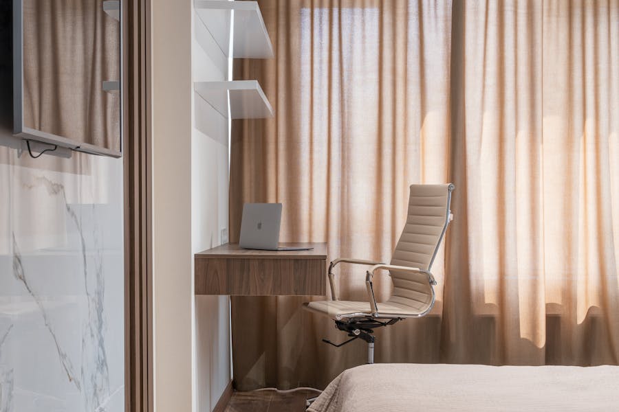 Un piccolo studio in camera da letto con sedia ergonomica che si adatta all'arredamento